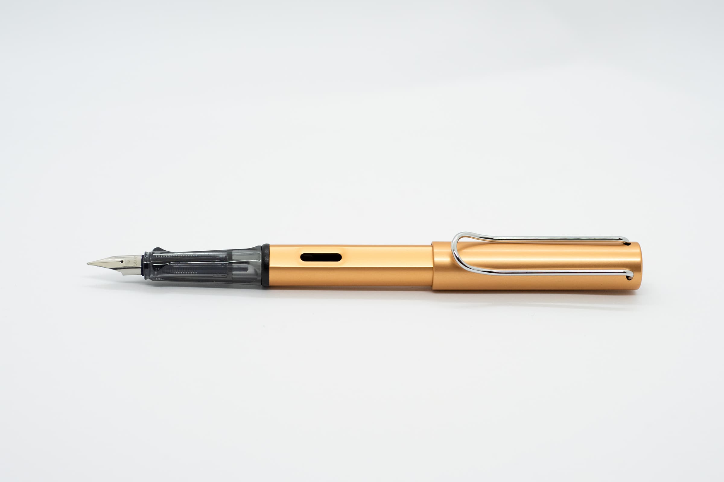 白い背景に横向きに置いたLAMY AL-star ブロンズ。黄みを帯びたブロンズの軸とキャップ、透明スモークのグリップとシルバーのニブ、クリップ
