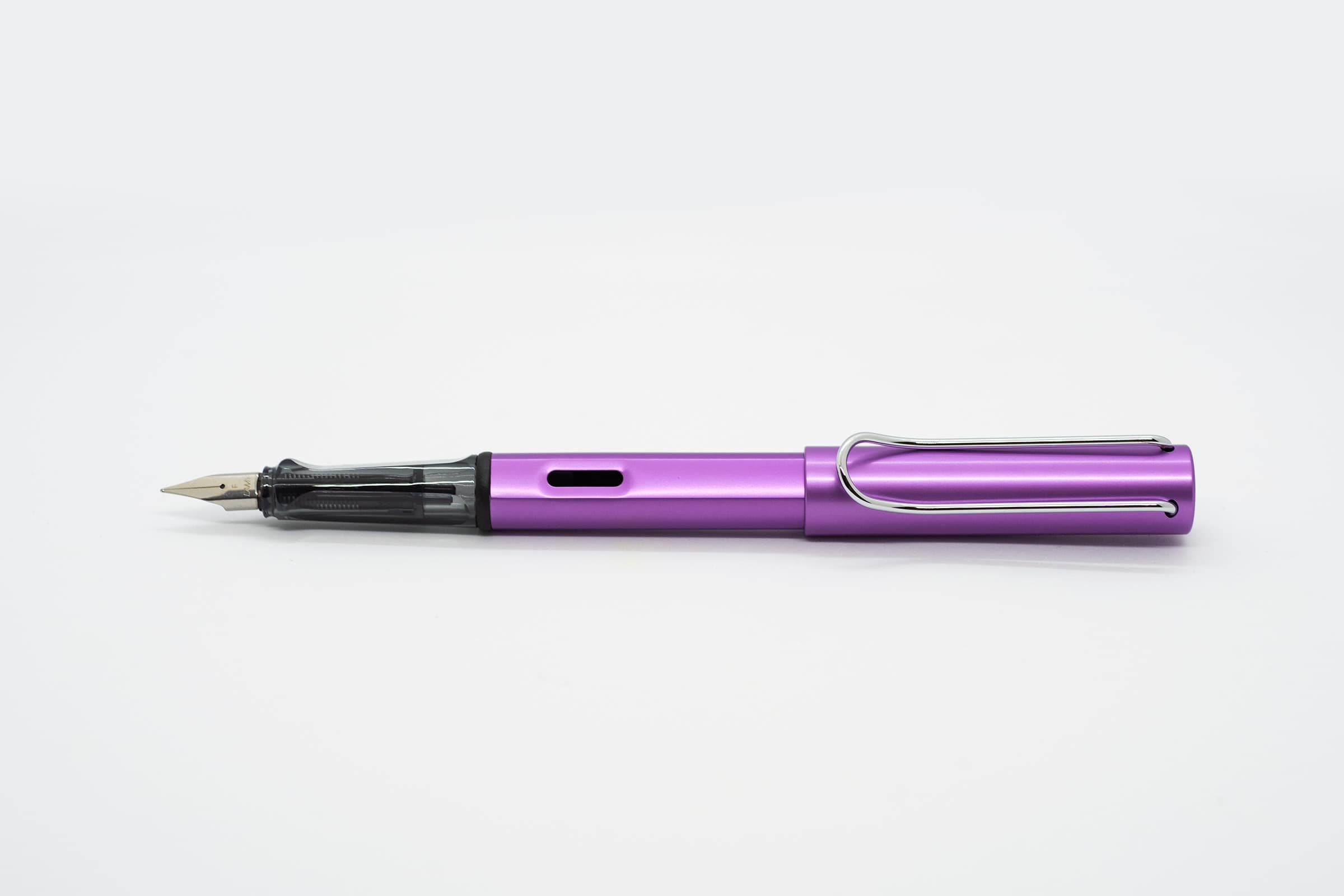 白い背景に横向きに置いたLAMY AL-star ライラック。明るい紫の軸とキャップ、透明スモークのグリップとシルバーのニブ、クリップ