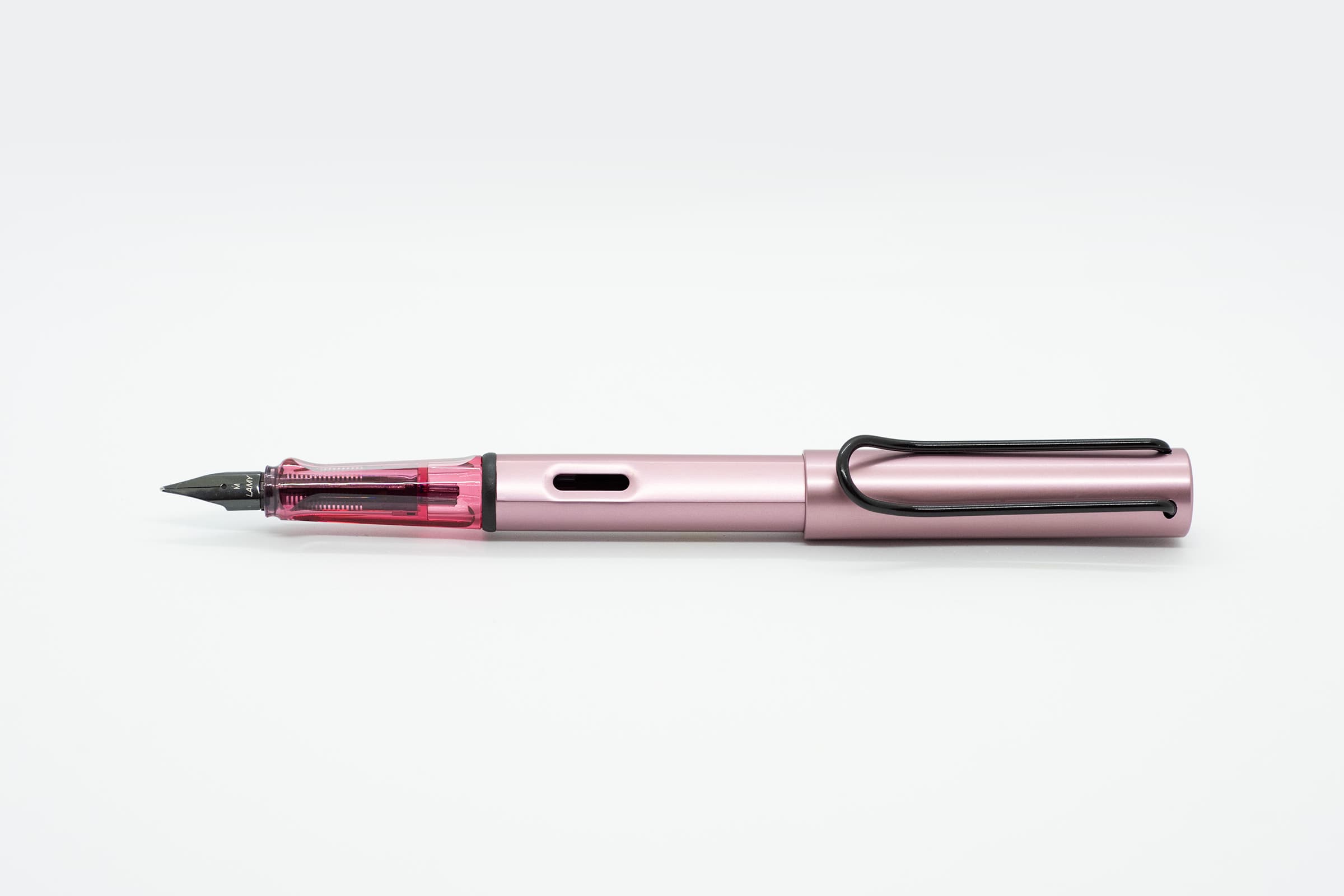 白い背景に横向きに置いたLAMY AL-star オータムピンク。淡いピンクの軸とキャップ、透明ピンクのグリップと黒いニブ、クリップ