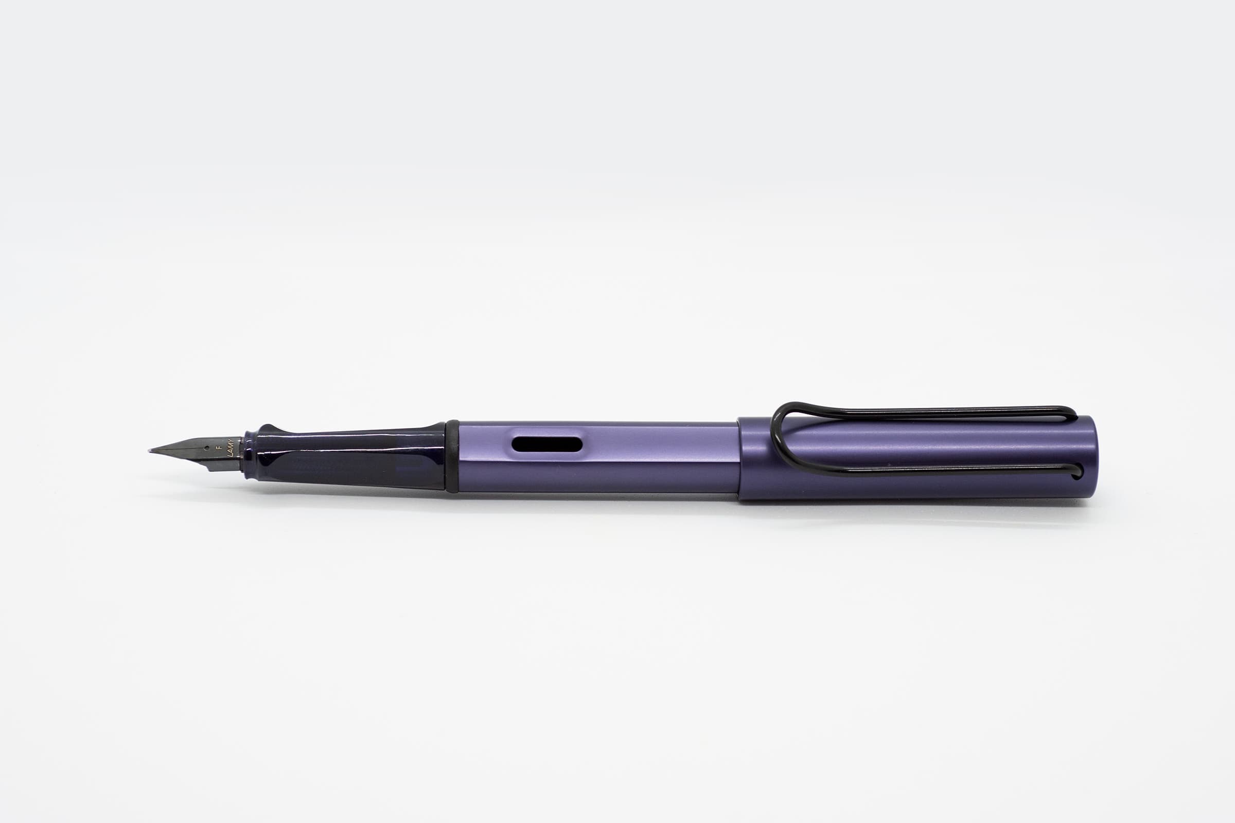 白い背景に横向きに置いたLAMY AL-star ダークダスク。濃い紫の軸とキャップ、暗色の透明グリップと黒いニブ、クリップ