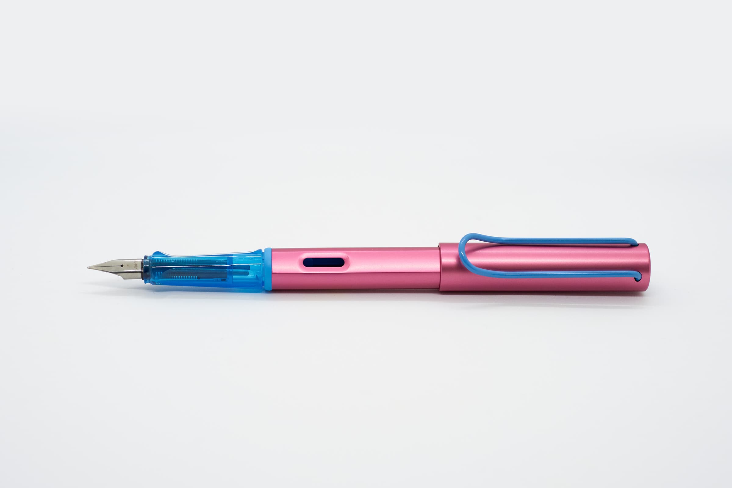 白い背景に横向きに置いたLAMY AL-star ローラースケート。ピンクの軸とキャップ、透明ブルーのグリップとブルーのクリップ