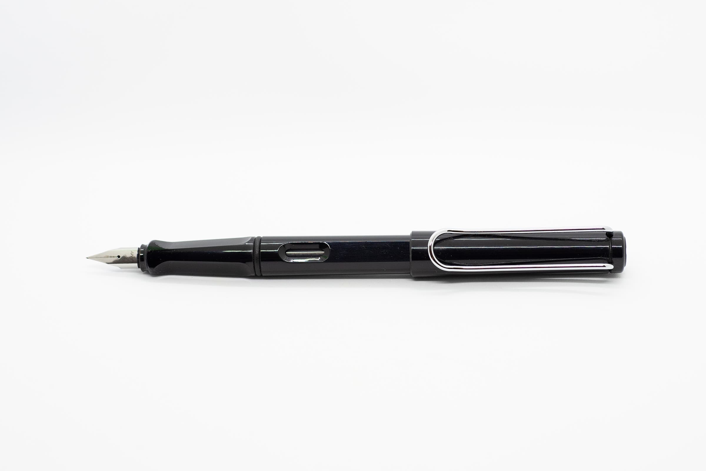 白い背景に横向きに置いたLAMY Safari ブラック。光沢のある黒い軸とキャップ、シルバーのニブとクリップ