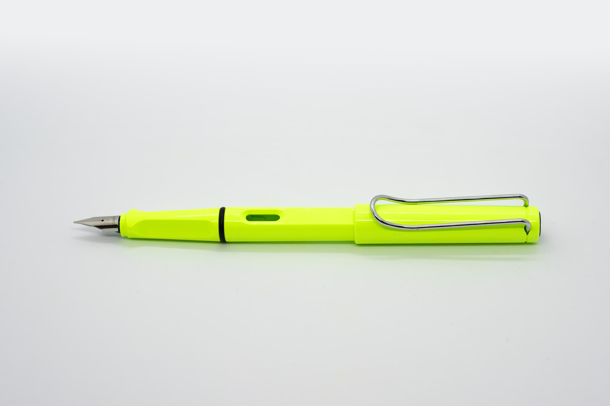 白い背景に横向きに置いたLAMY Safari ネオンライム。蛍光黄緑色の軸とキャップ、シルバーのニブとクリップ